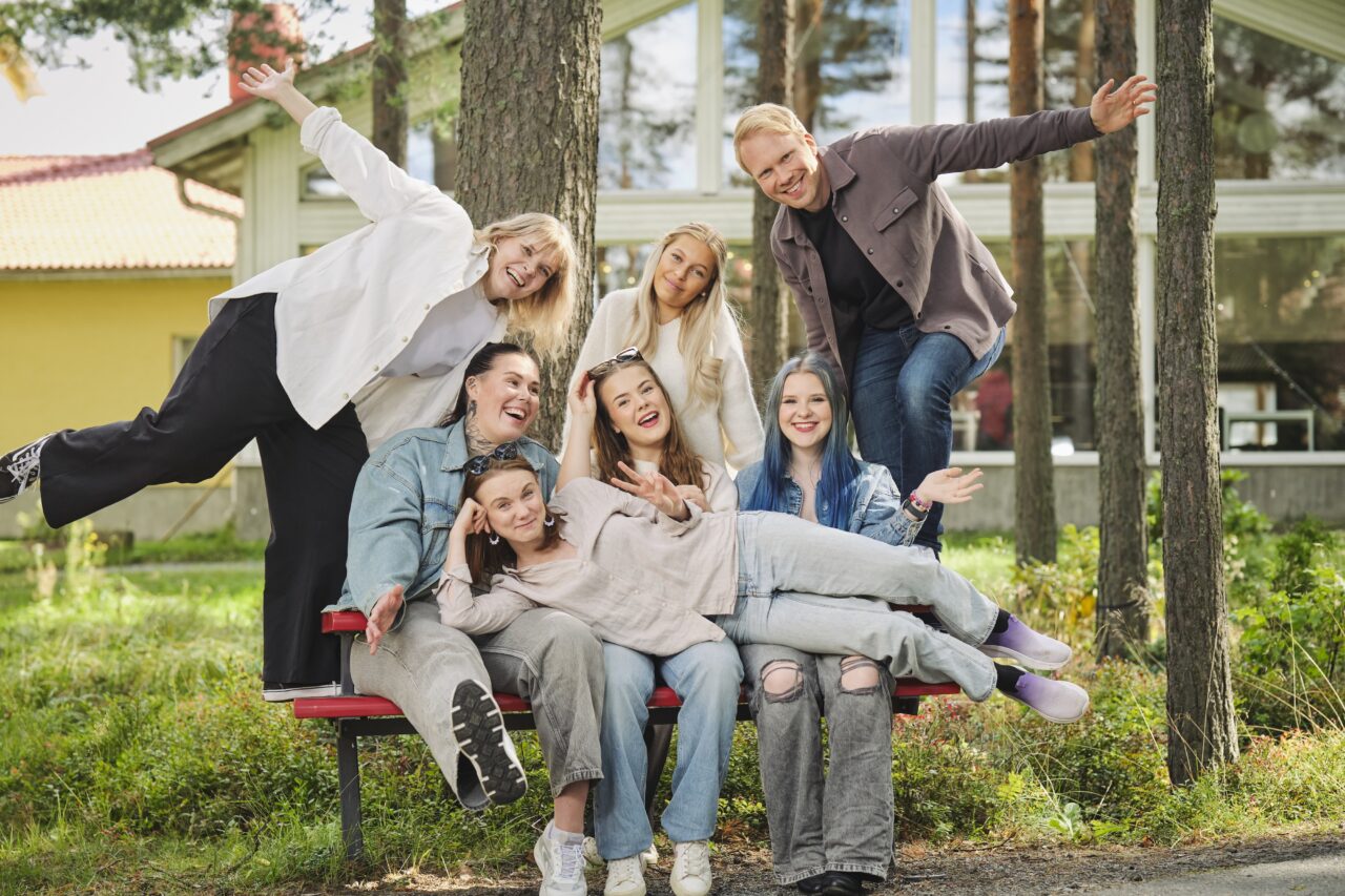 Ryhmä nuoria aikuisia ja ohjaajia viettää aikaa yhdessä ulkona Diakontalon pihapiirissä.